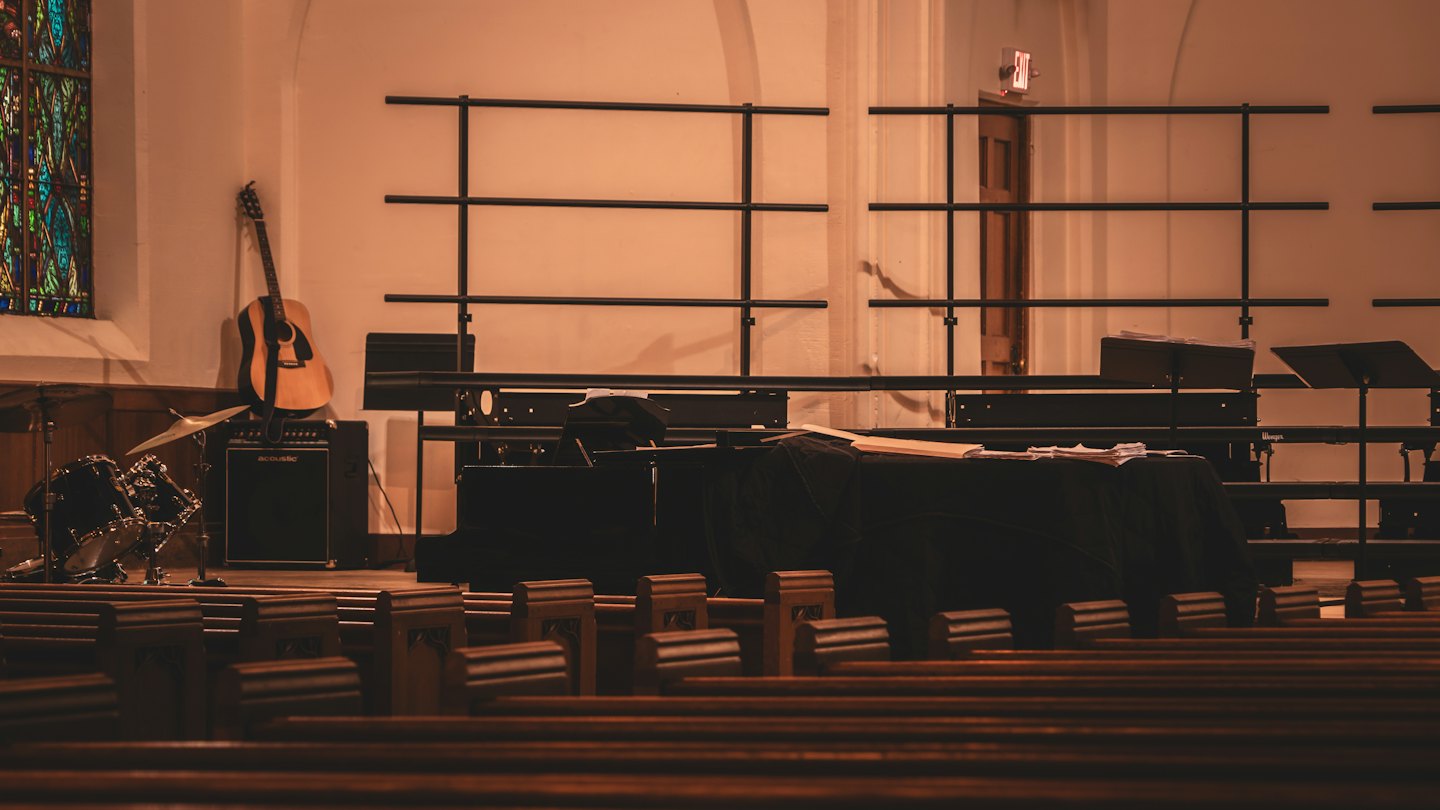 Instrumenty muzyczne na scenie kościelnej z drewnianymi ławkami.